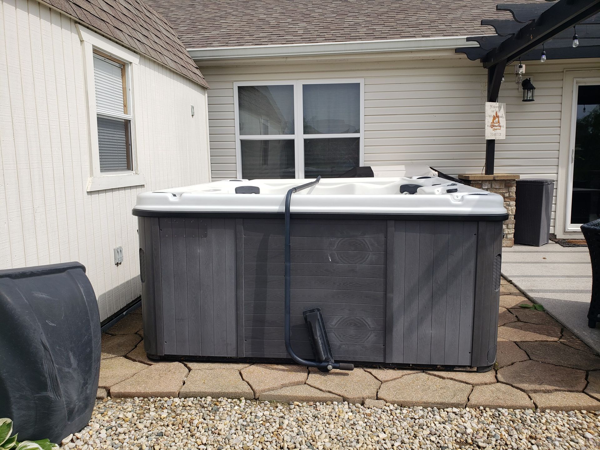 A hot tub is sitting on a patio in front of a house.