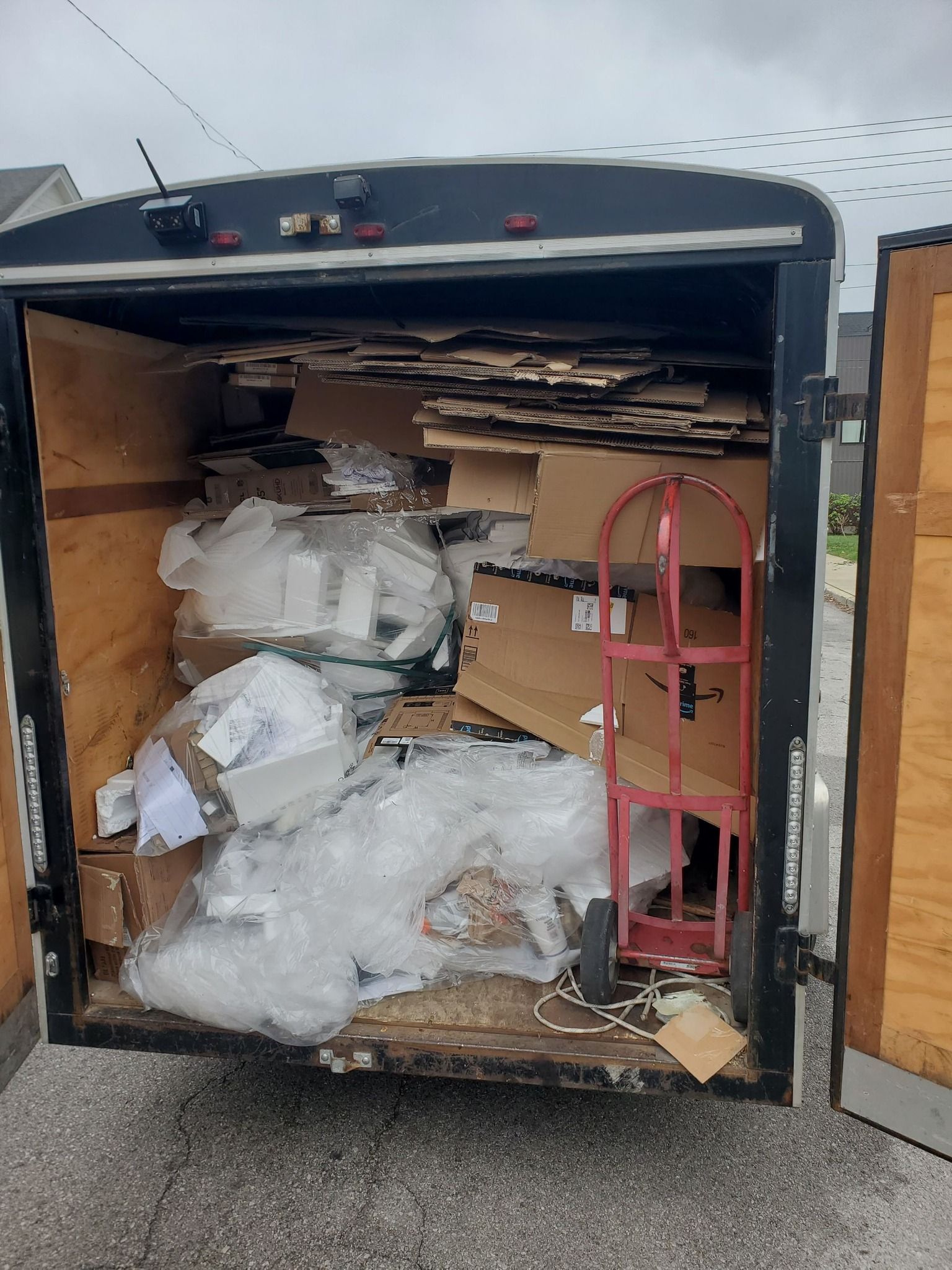 A trailer filled with lots of cardboard boxes and plastic wrap. A trailer filled with lots of cardboard boxes and plastic wrap.
