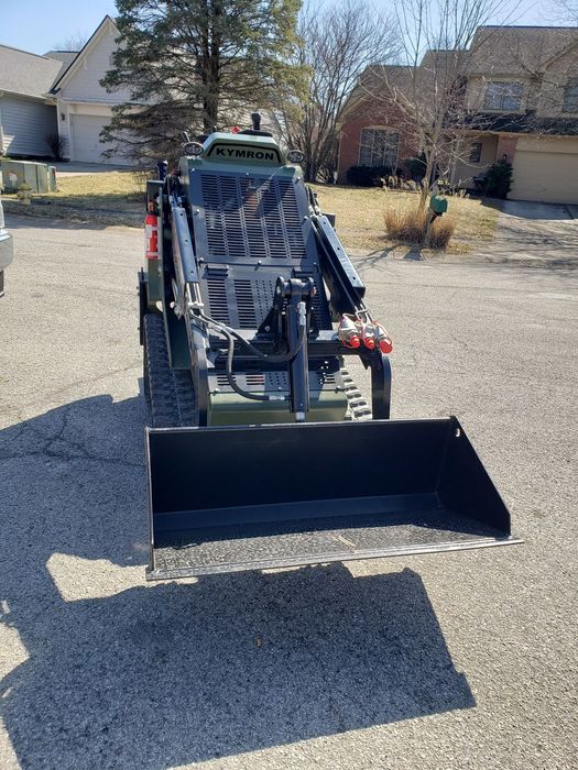 A tractor with a bucket attached to it is parked in a gravel lot. A tractor with a bucket attached to it is parked in a gravel lot.
