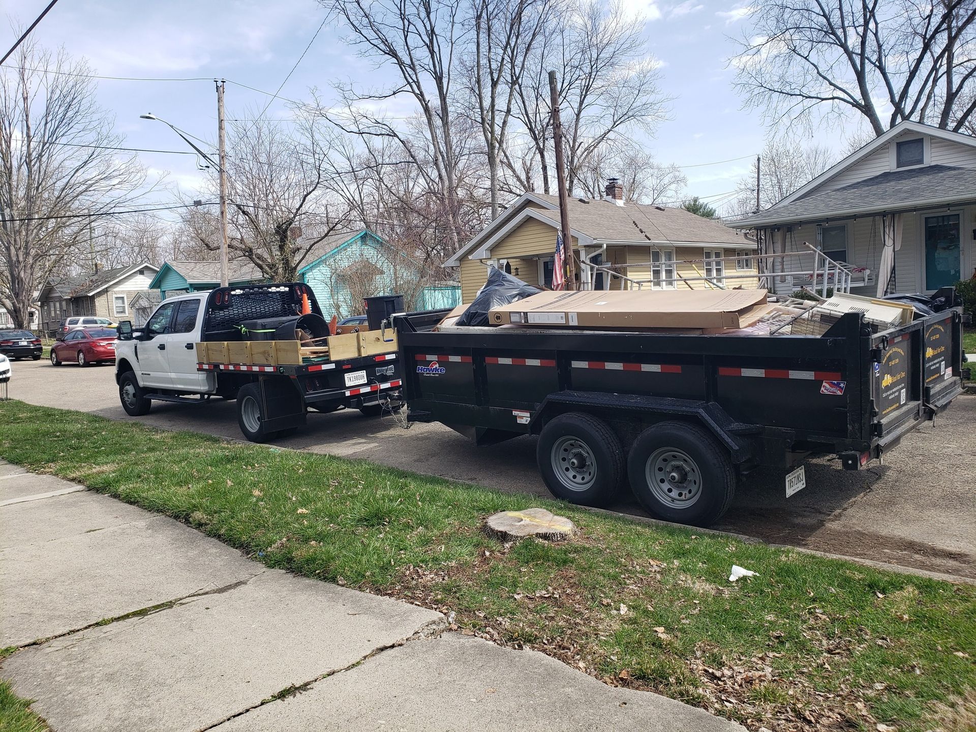 A dumpster is being towed by a truck in a driveway. A dumpster is being towed by a truck in a driveway.