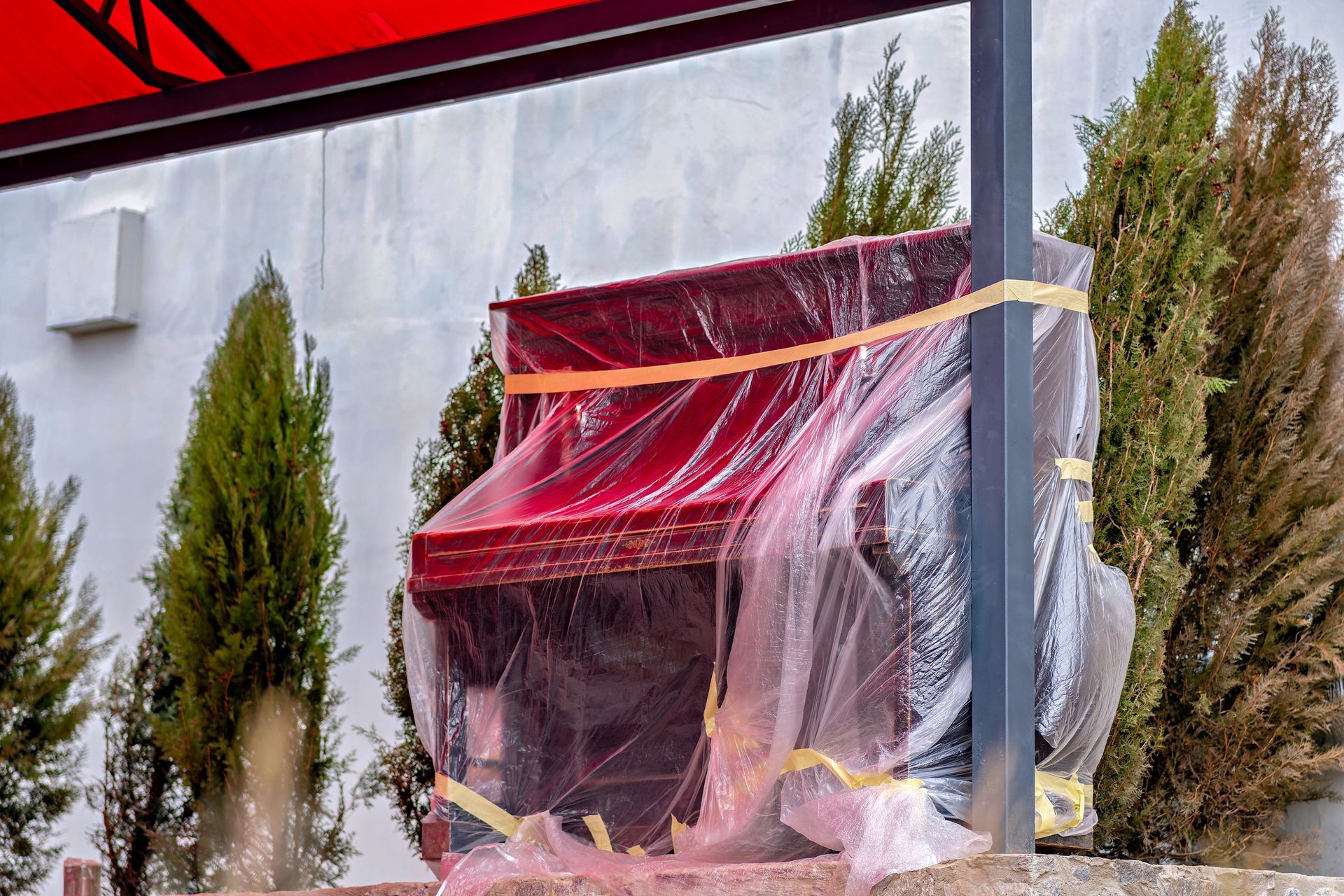 A dumpster is parked on the side of the road next to a red dolly.