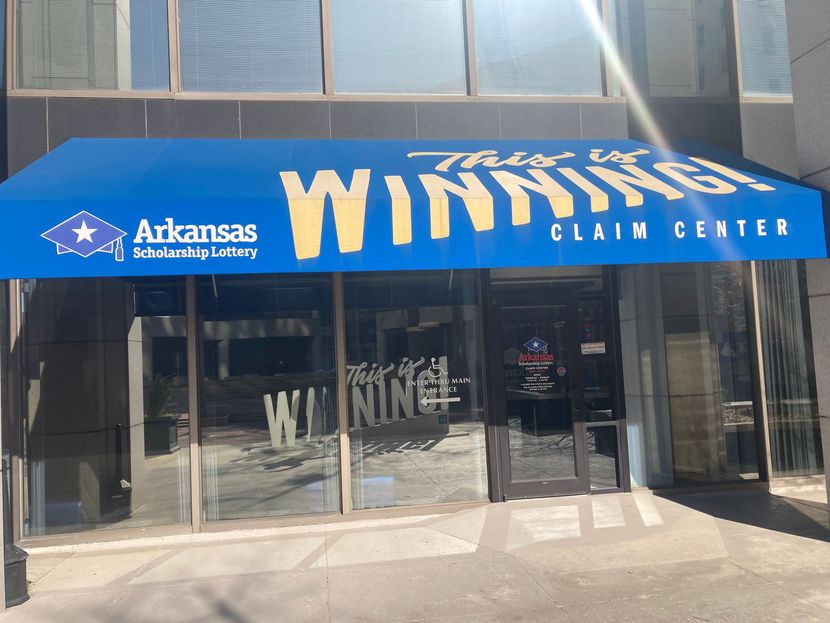 An Arkansas Scholarship Lottery claim center storefront with a blue awning displaying the text