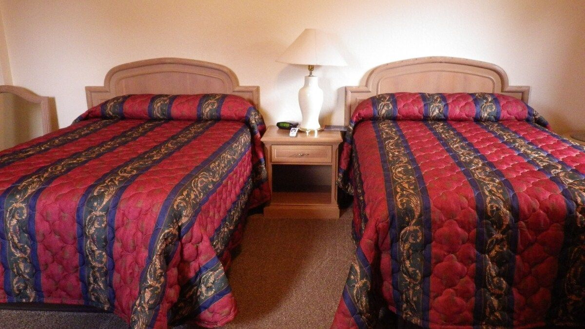 A hotel room with two beds and a lamp