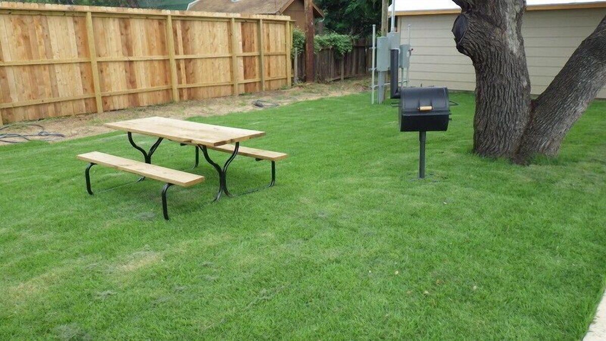 There is a picnic table and a grill in the backyard.