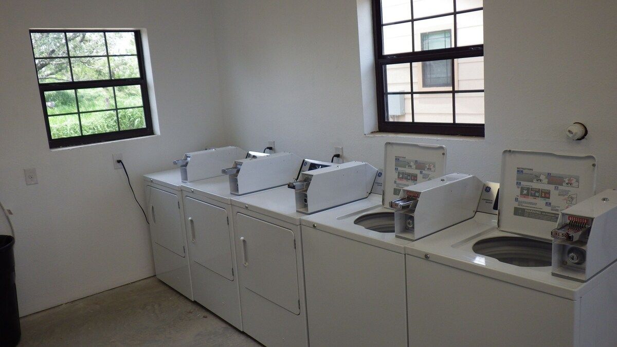 A laundry room with washers and dryers and a window.