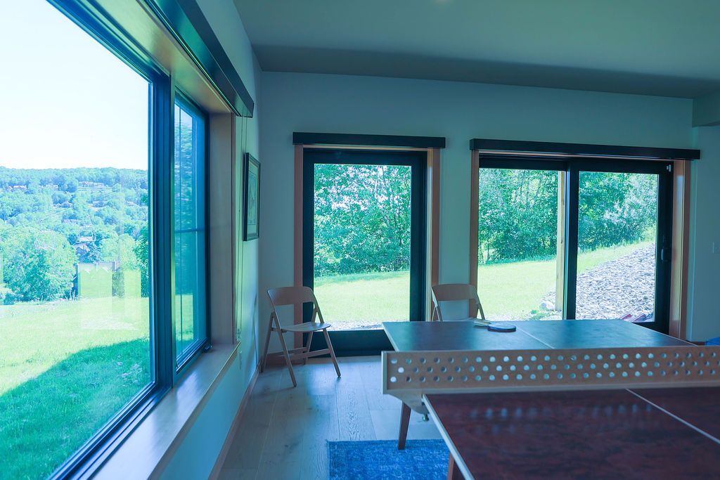 New build Modern living room with large windows overlooking a green landscape. Project by Schultz- Vogt Construction in Ellicottville NY