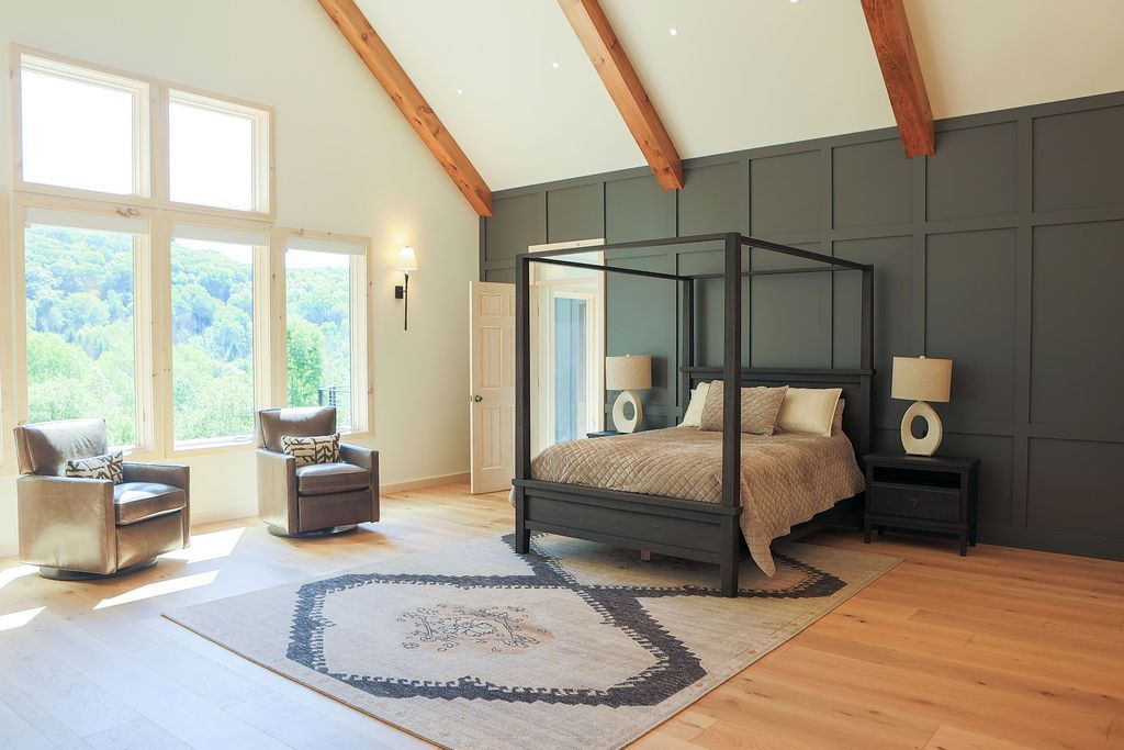 Bright bedroom with four-poster bed, large windows, wooden beams, and a patterned rug in Ellicottville NY Done By Schults-Vogt Construction