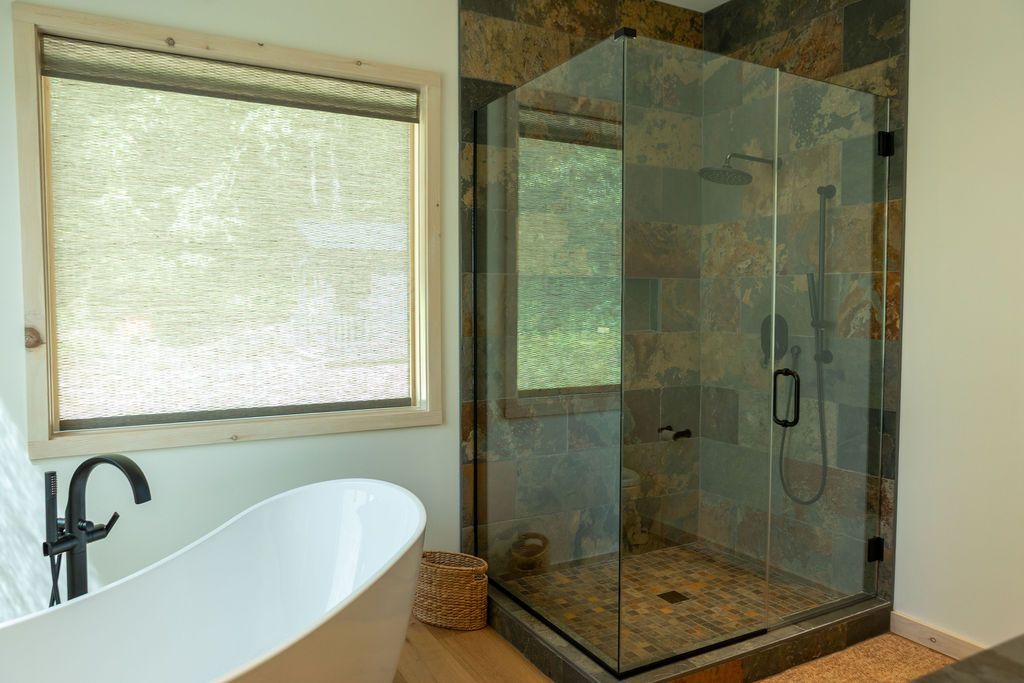 New Modern bathroom with freestanding tub, glass shower, and large window with a blind