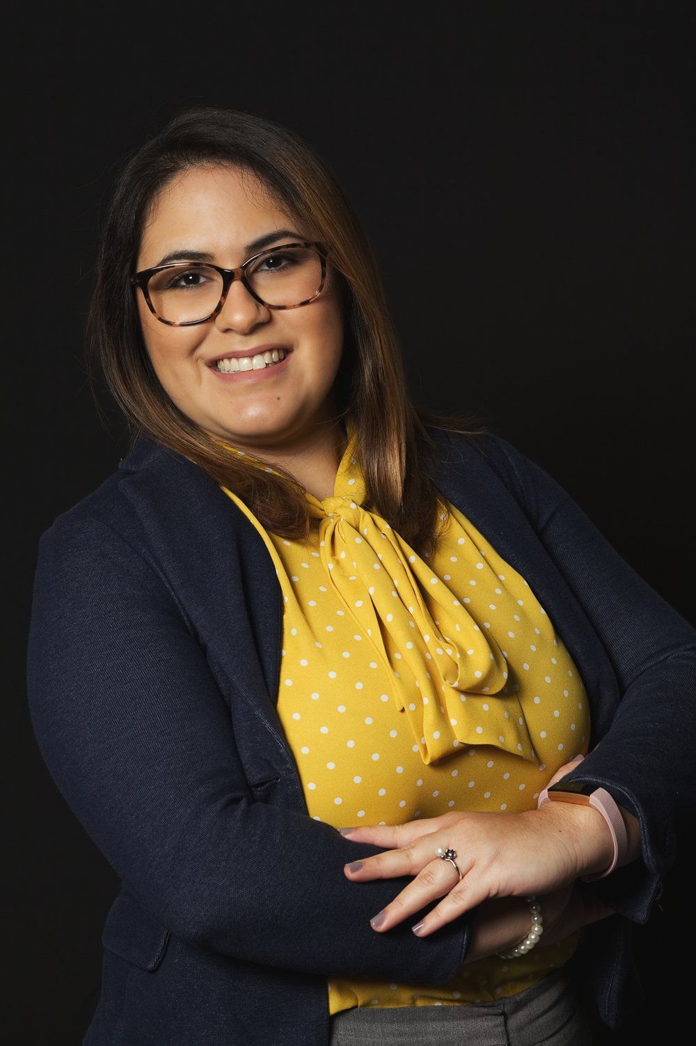 A woman wearing glasses and a yellow shirt is posing for a picture.