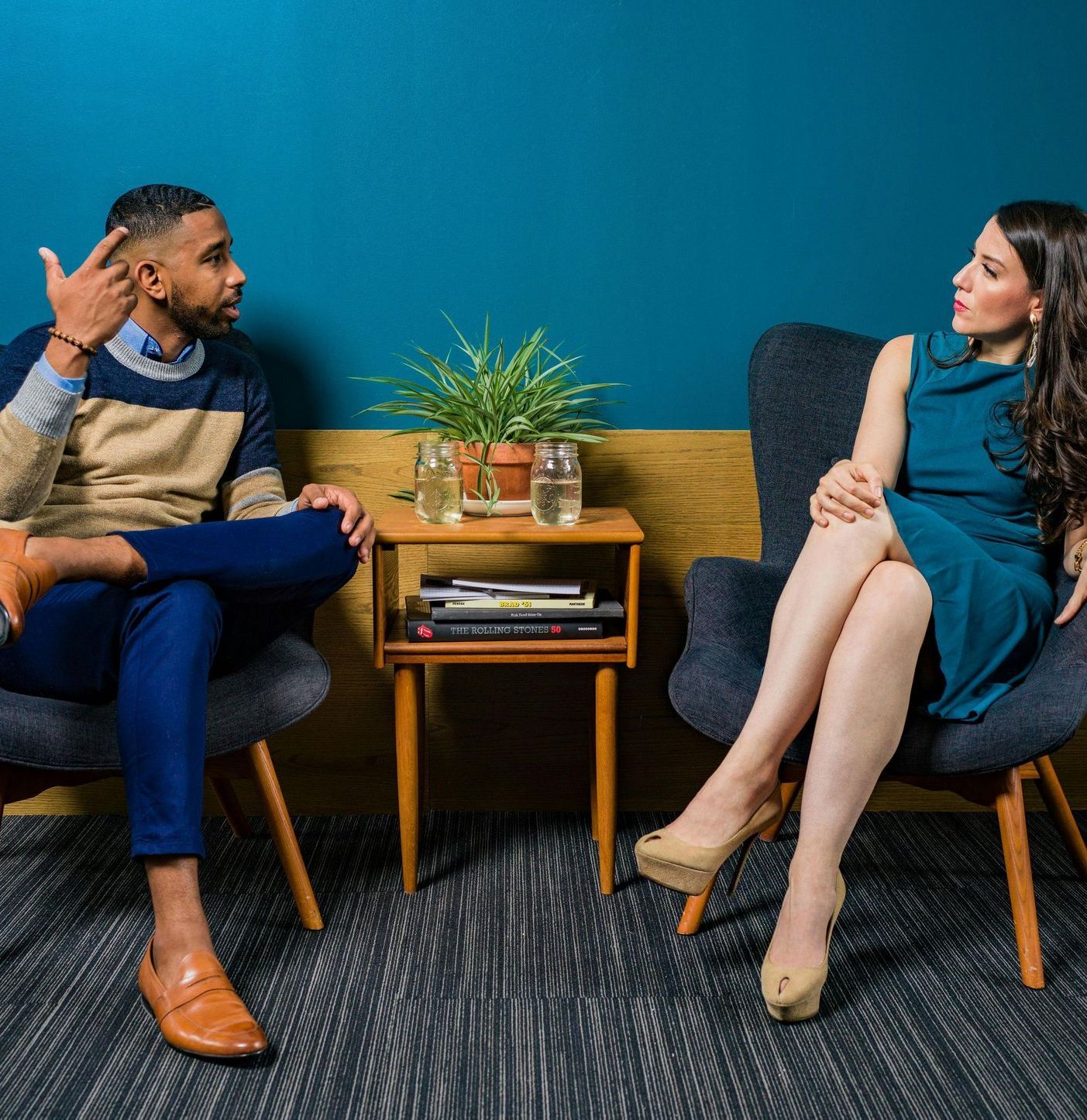 A man and a woman are sitting in chairs talking to each other