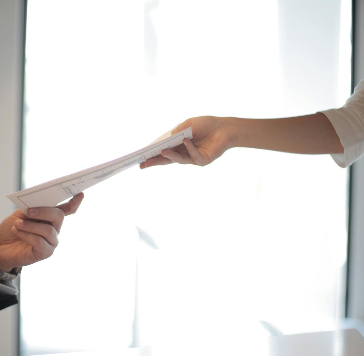 A person is handing a piece of paper to another person
