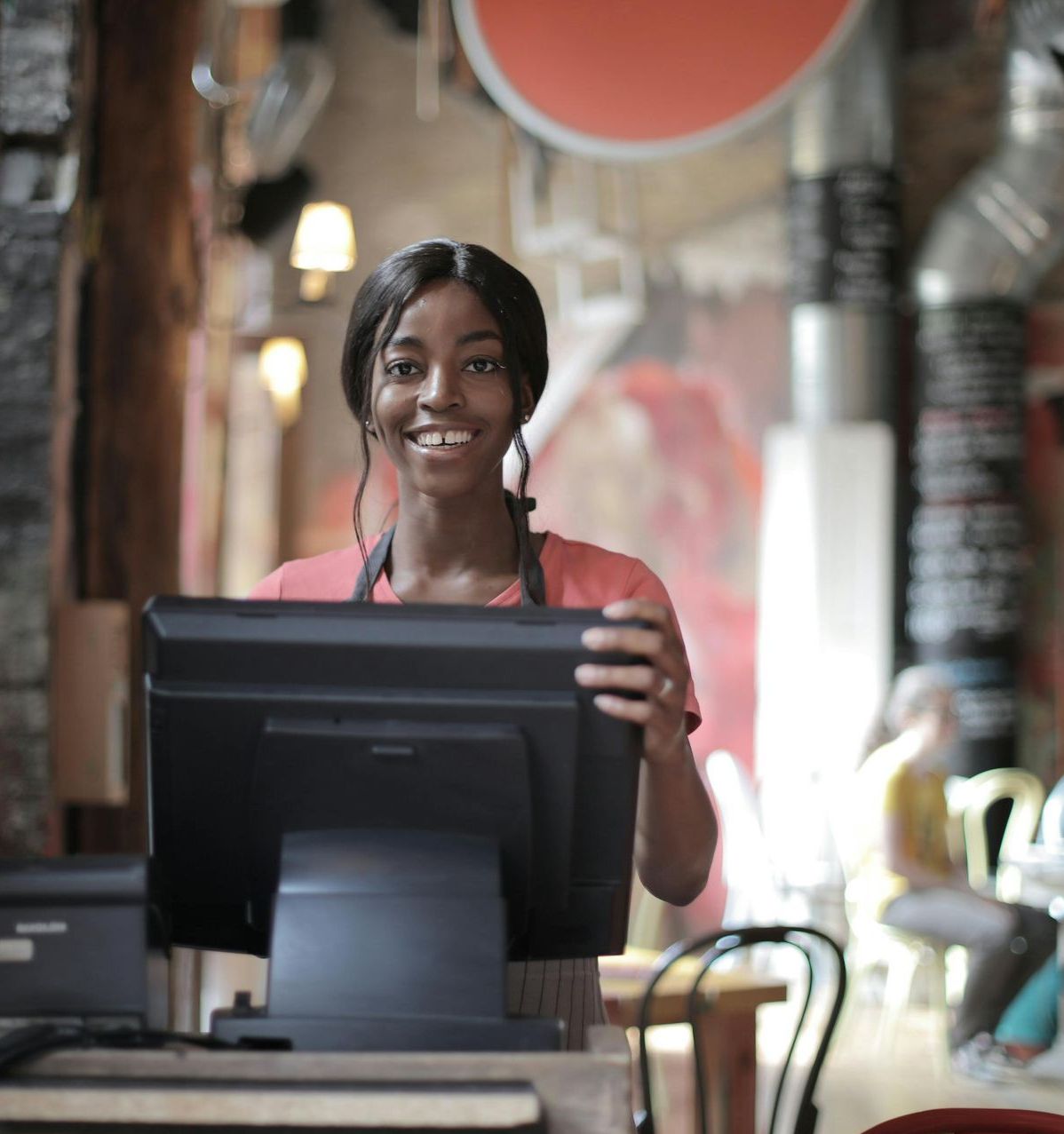 A woman is standing in front of a computer and smiling