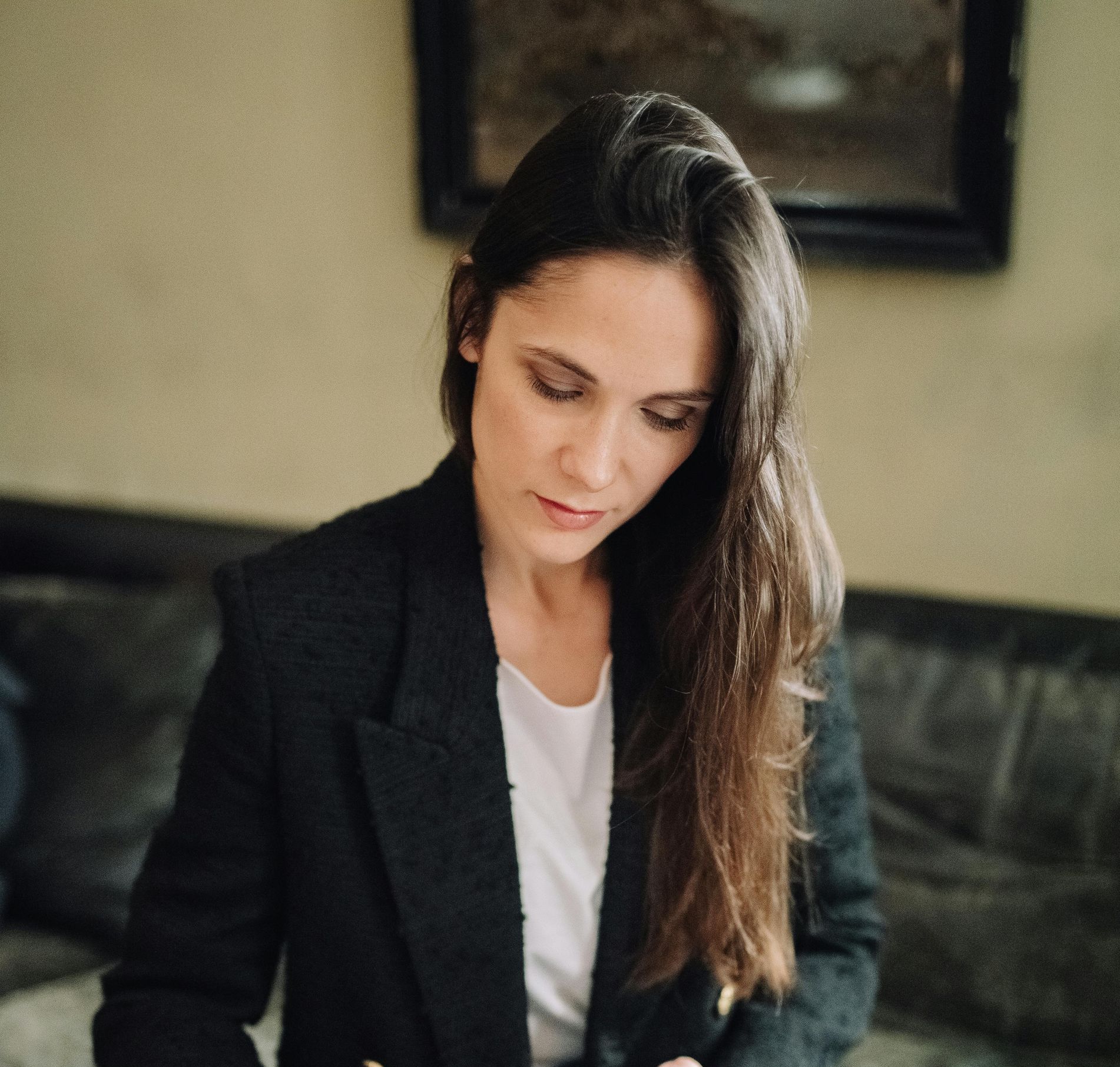 A woman in a black jacket is sitting on a couch