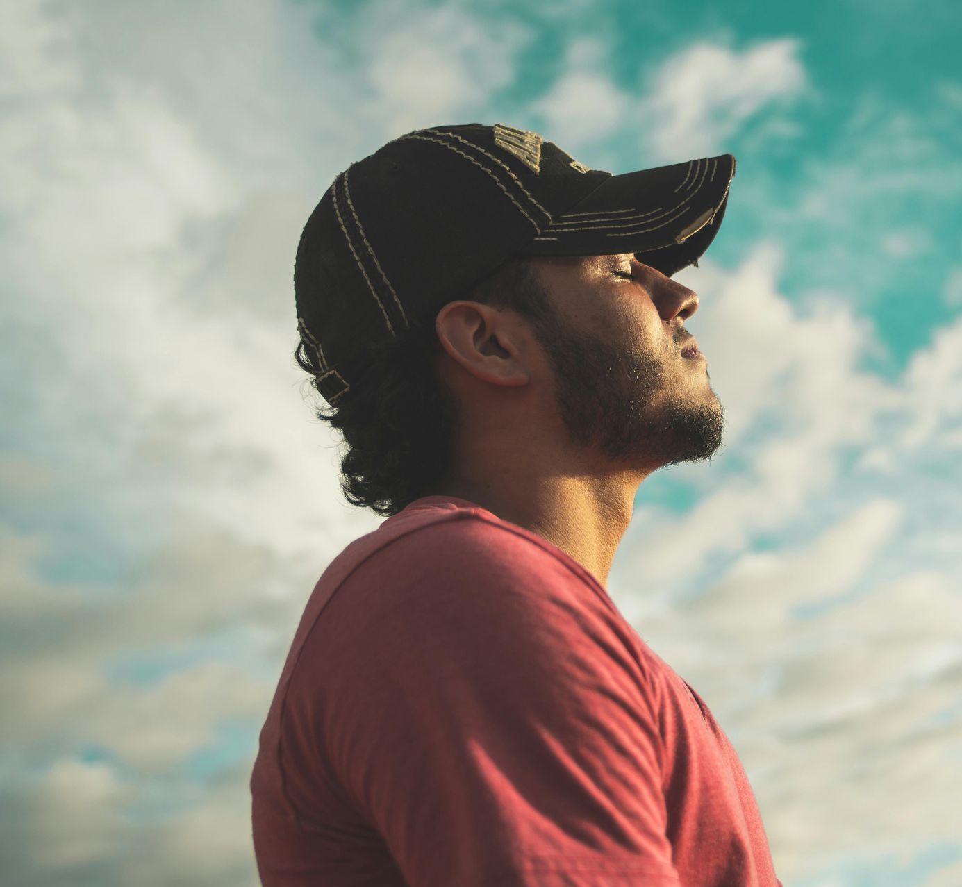 A man wearing a baseball cap looks up at the sky