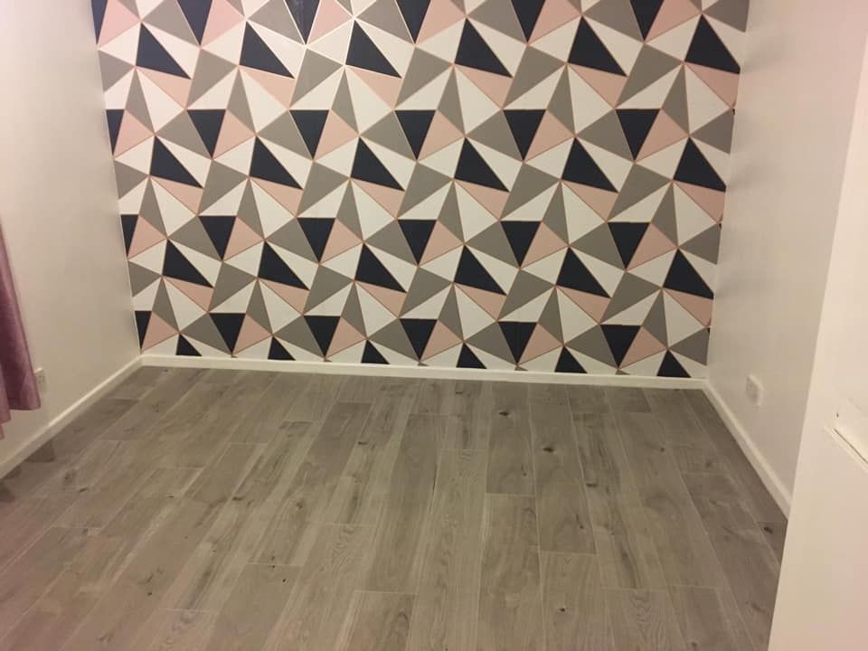 Grey wood-effect laminate flooring in a room with a patterned feature wall