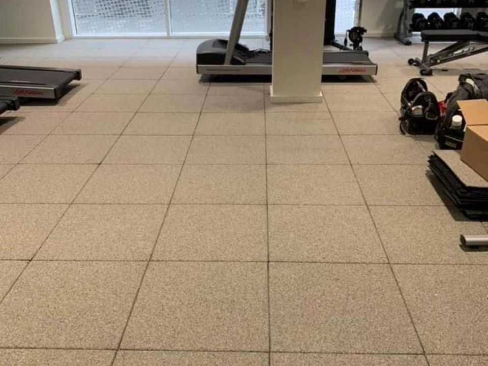 Speckled rubber gym flooring tiles fitted across a gym with treadmills and weights
