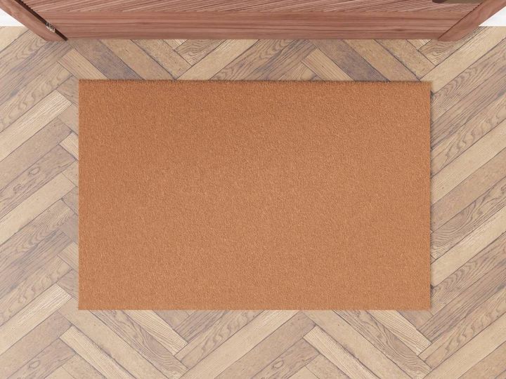 Plain terracotta-coloured microfibre door mat on a herringbone floor