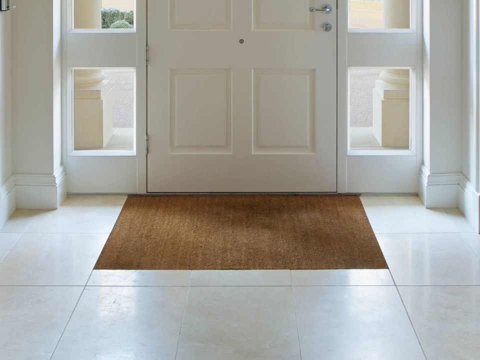 Coir door mat set into the tiled floor of a hallway, just inside the front door