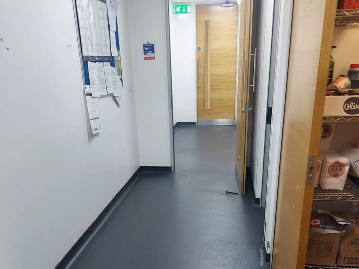 Safety vinyl coved up the wall along a kitchen corridor leading to a dry goods store