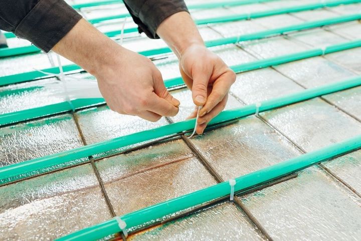 Wet underfloor heating pipework being installed before a new floor