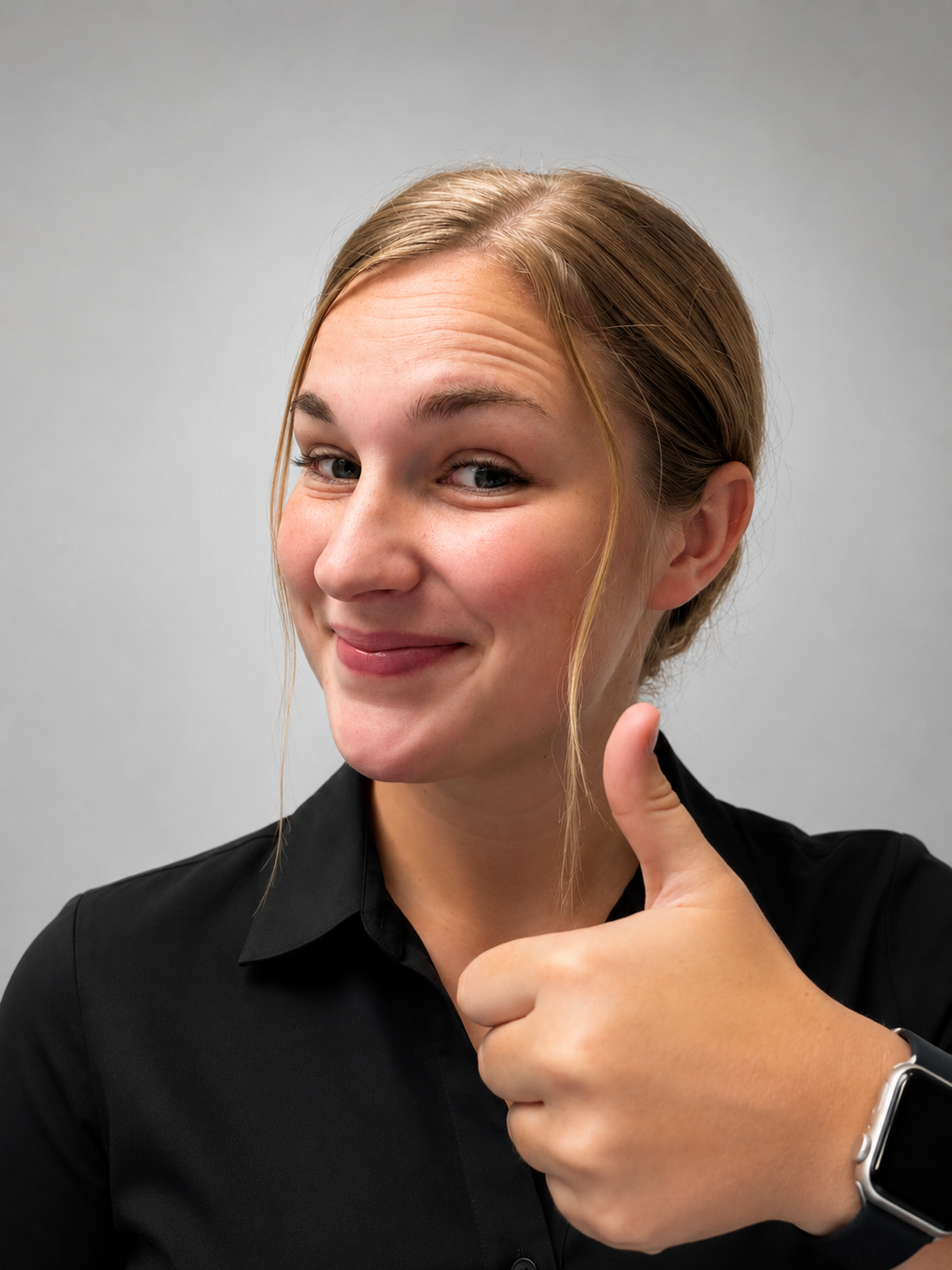 Person smiling and giving a thumbs-up in a black shirt against a gray background