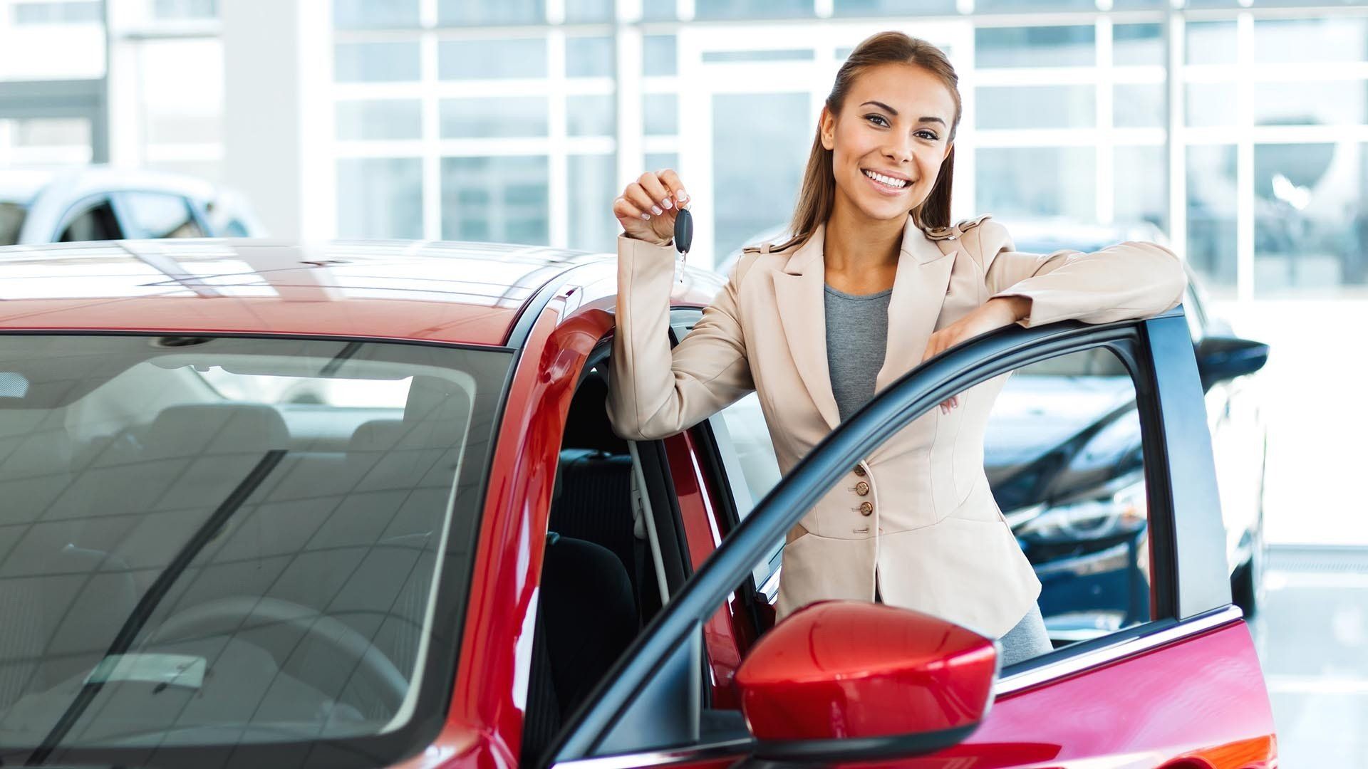 woman holds up keys to red car