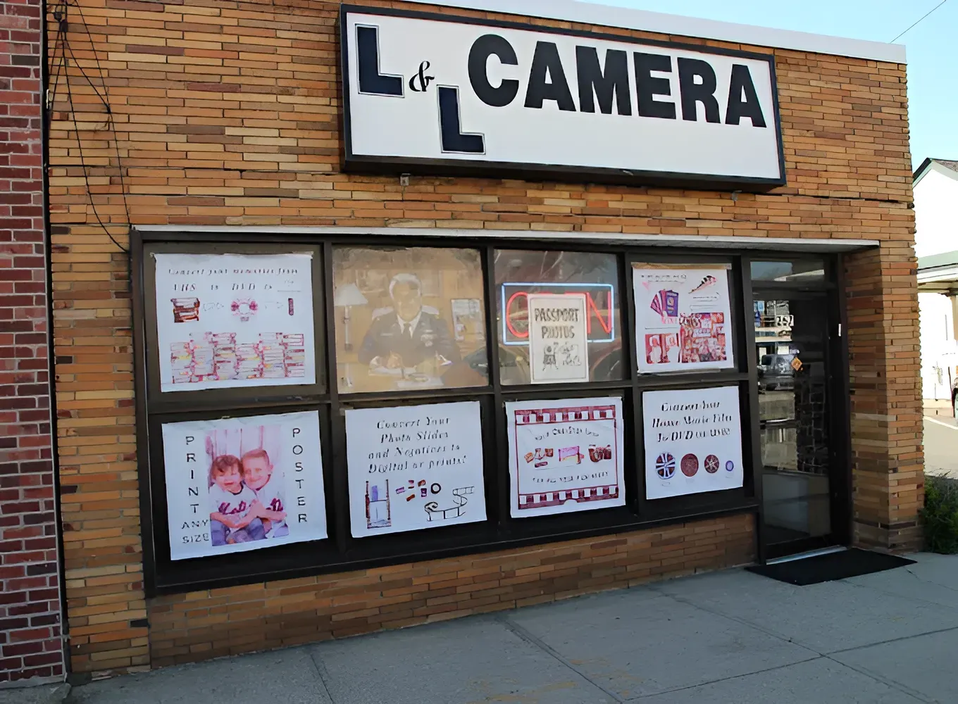 Storefront of “La Camera” with brick exterior and posters in the windows.