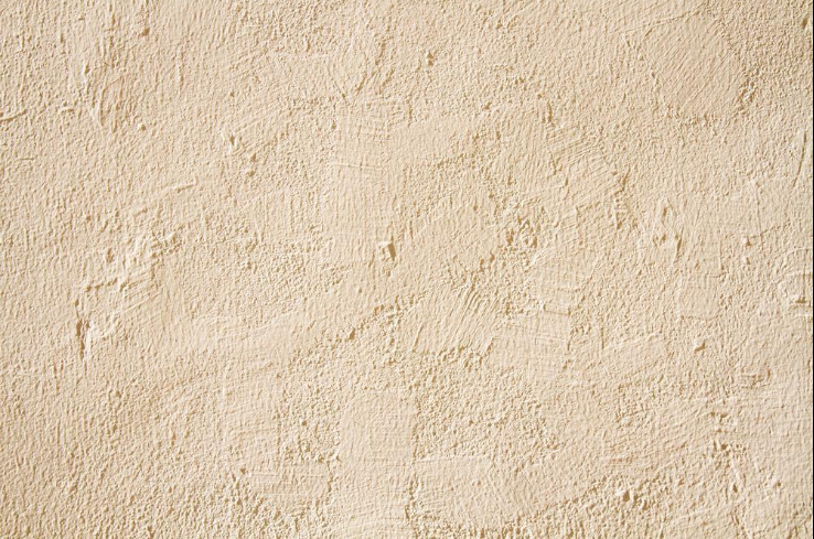 “Close-up of a light beige stucco wall texture showing a rough, even exterior finish from a stucco service in Henderson, NV”