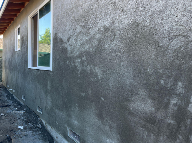 “Side of a home with a newly applied gray stucco finish around windows during a stucco service in Henderson, NV”