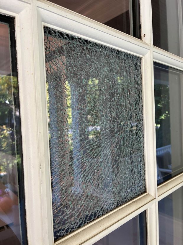 Cracked windowpane with shattered safety glass in a white-framed window