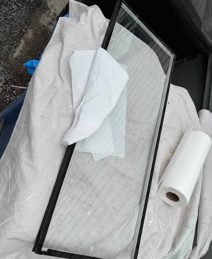 Two black-framed glass panels on a cloth-covered surface beside a roll of paper towels.