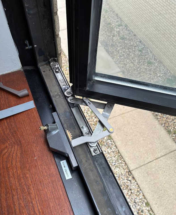 Open glass door with damaged floor hinge and metal bracket on a dark frame
