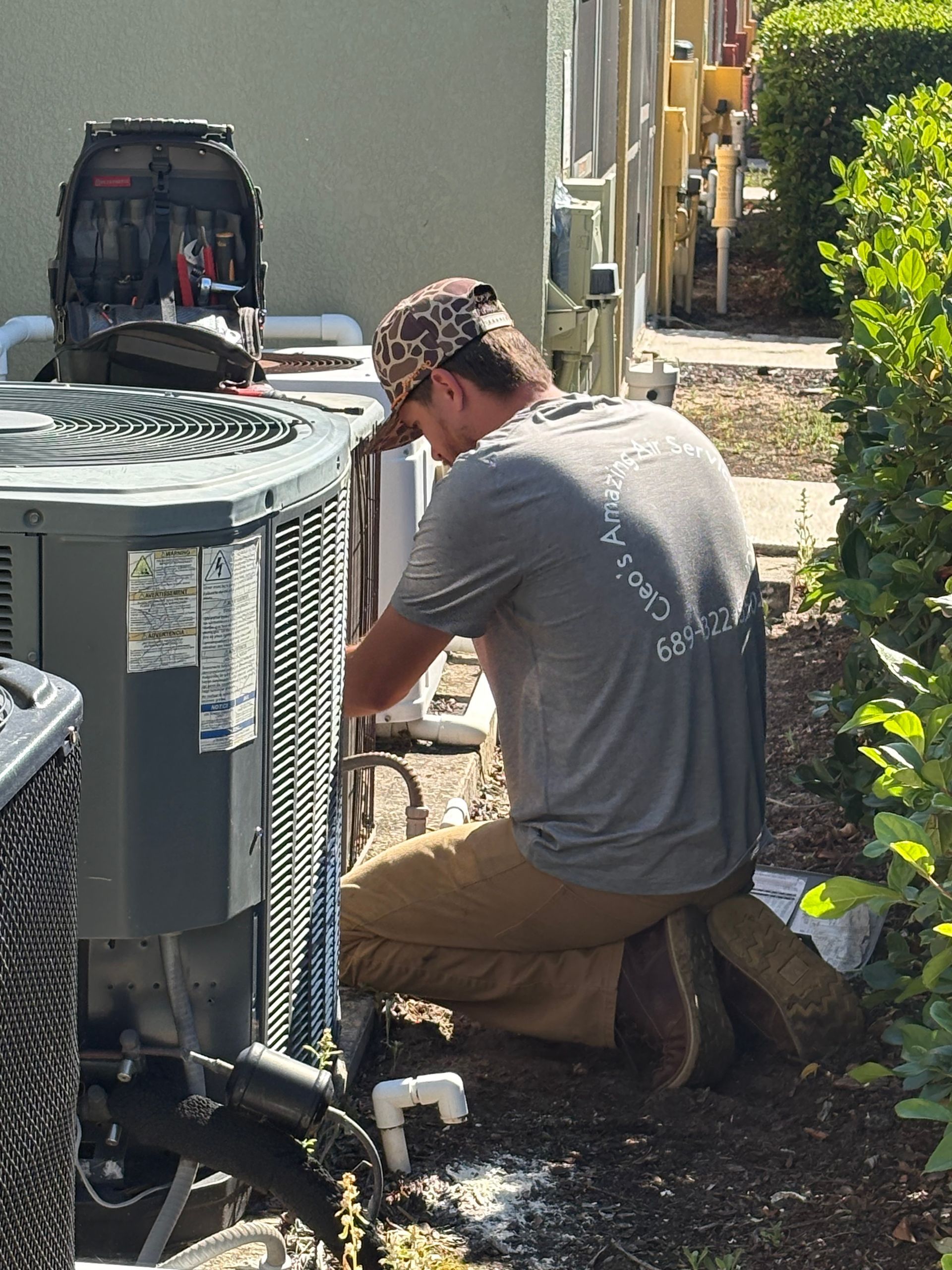 A man is working on an air conditioner outside of a building.