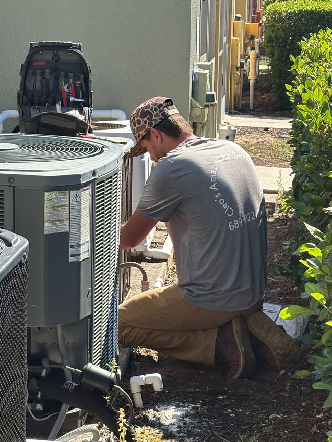 A man is working on an air conditioner outside of a building.