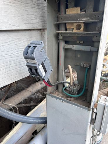 An open electrical service box mounted on a wall, showing a disconnected dual-pole breaker and exposed wiring.