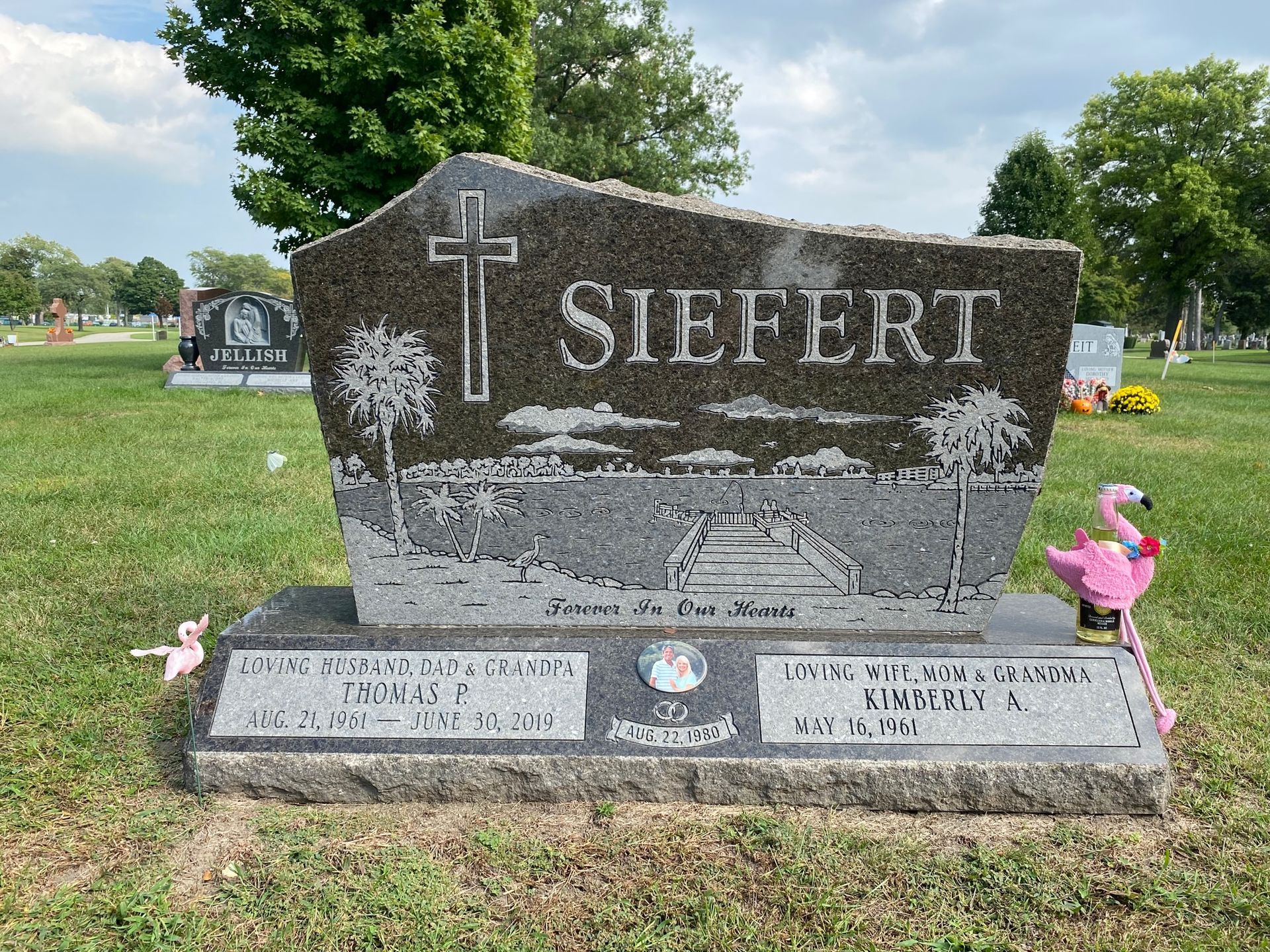 Tombstone engraved with POWER, flanked by flower vases in a grassy cemetery setting.