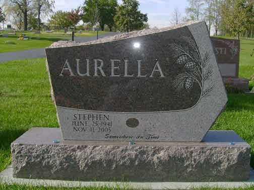 A granite gravestone inscribed with the name AURELLA and dates for Stephen, situated in a grassy cemetery.