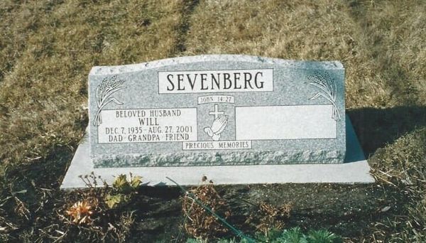 Gravestone in a grassy field, reading