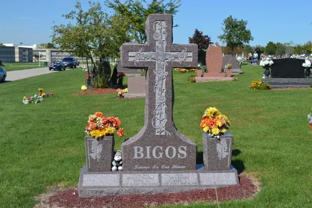 A stone gravestone in the shape of a cross engraved with 