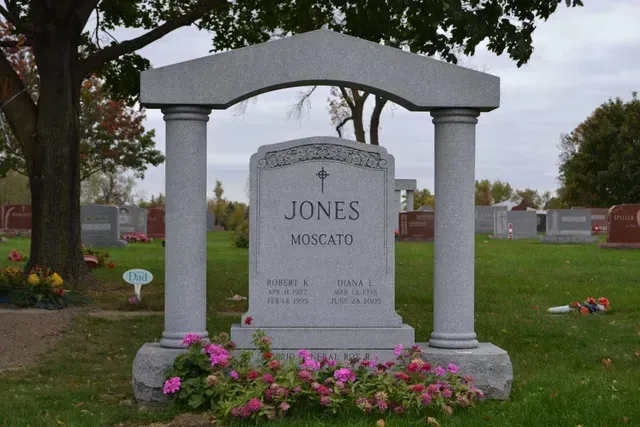 A grey, columned headstone inscribed with 