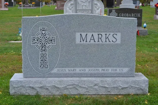 A gray granite headstone in a cemetery with the surname 