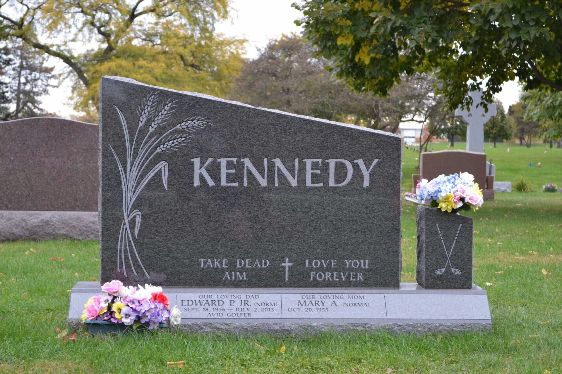 Gray Kennedy family tombstone with floral decorations in a cemetery.