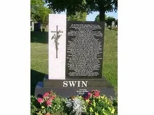 A granite tombstone with a cross engraving and a long inscription, featuring the name 