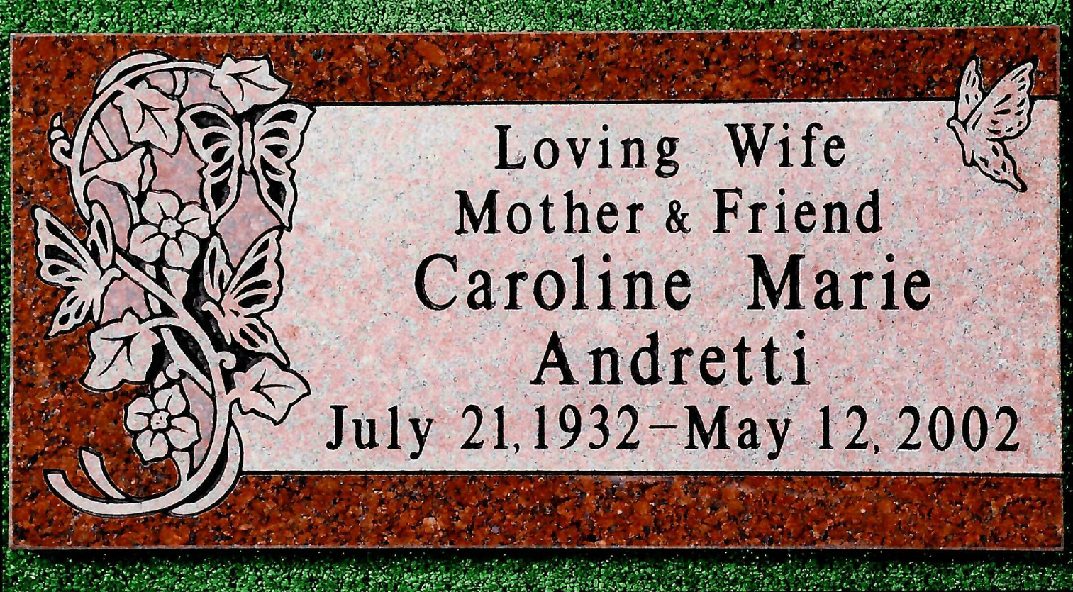 A polished, red granite memorial plaque engraved with butterflies, ivy, and the name