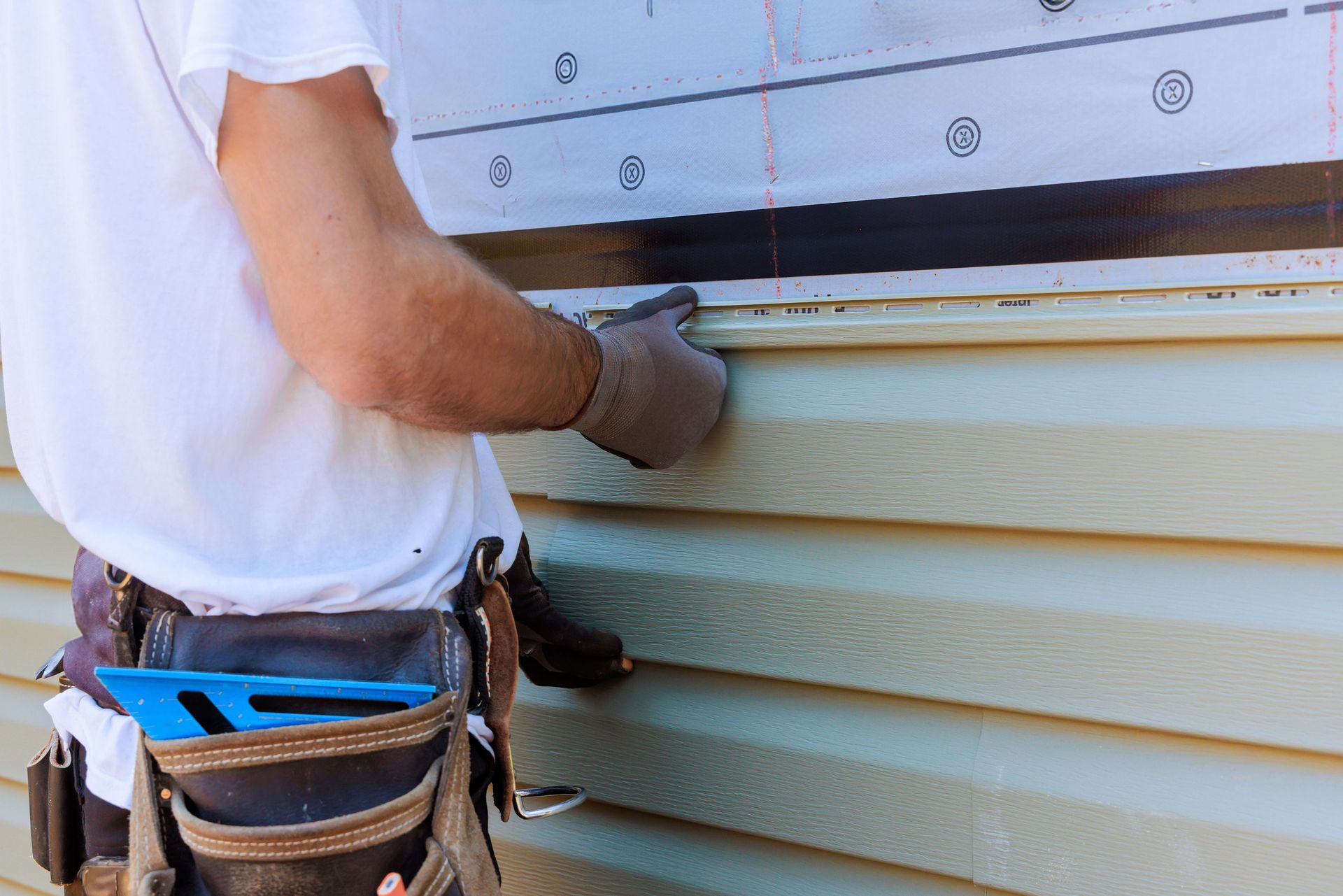 A person is using a drill to install a wooden fence.