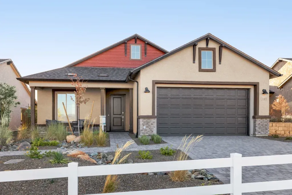 Single-story suburban house with a gray garage, red and tan roof, and white fence in front.