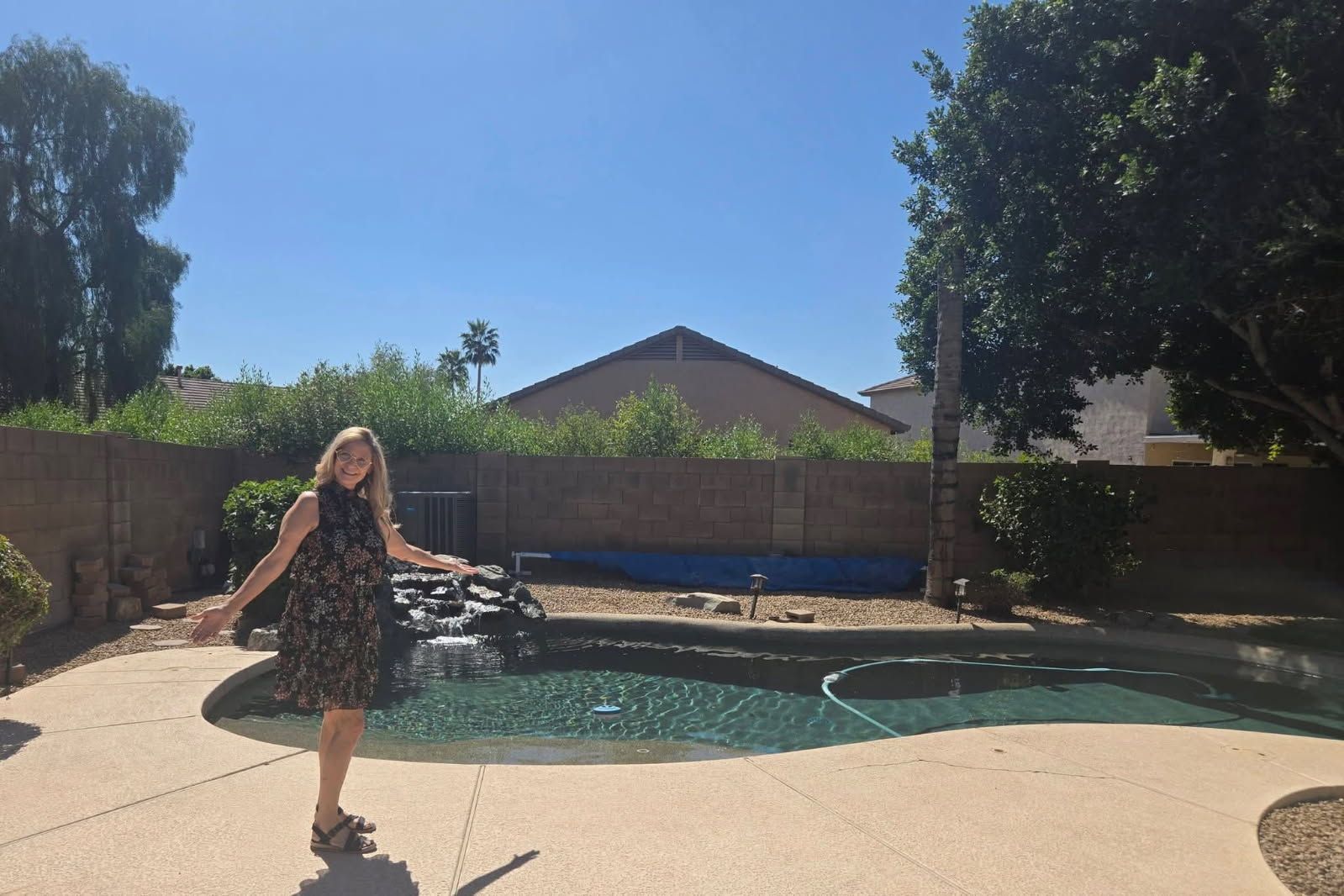 Woman standing by a backyard swimming pool on a sunny day