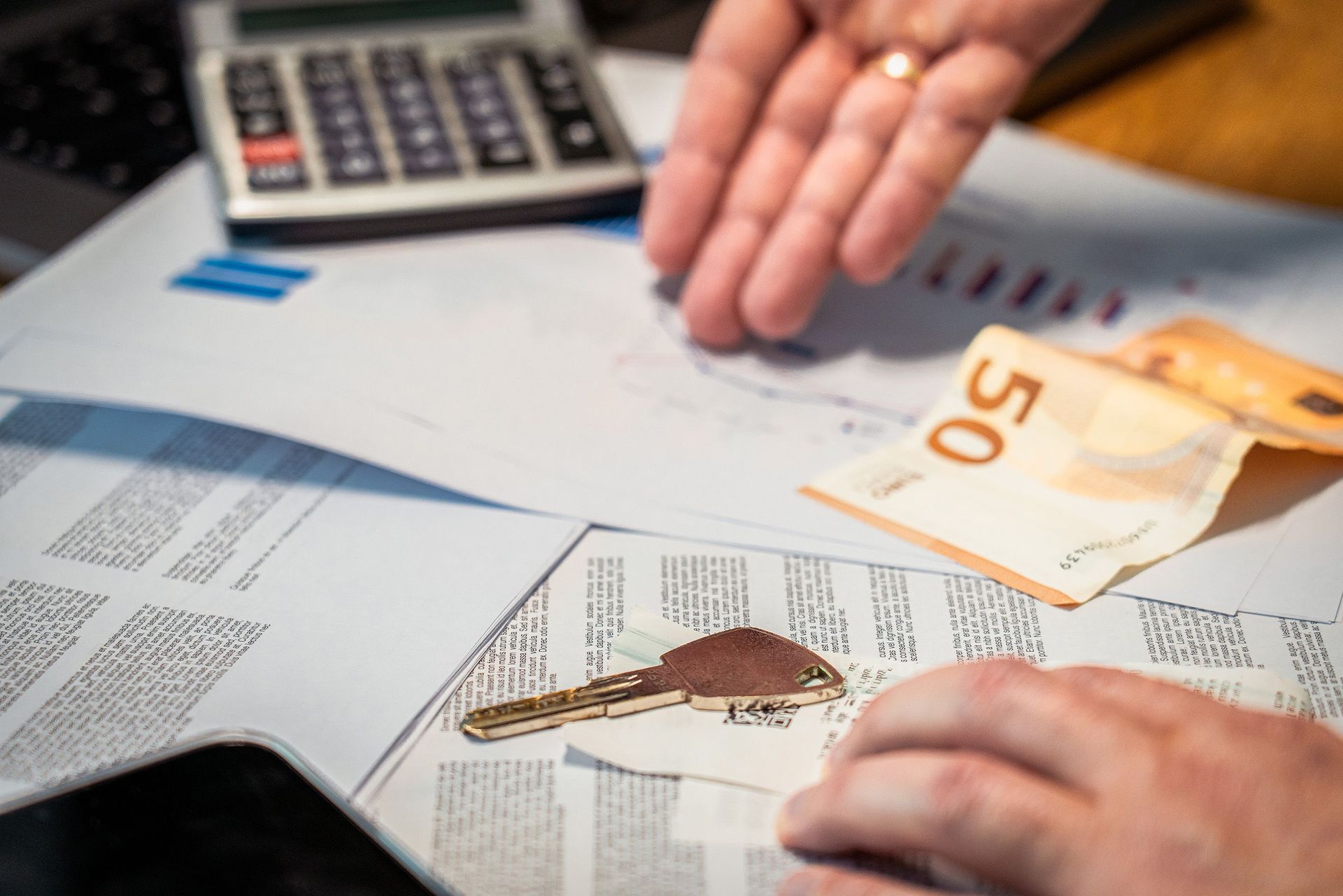 Hands counting euro banknotes over financial documents and a calculator on a desk