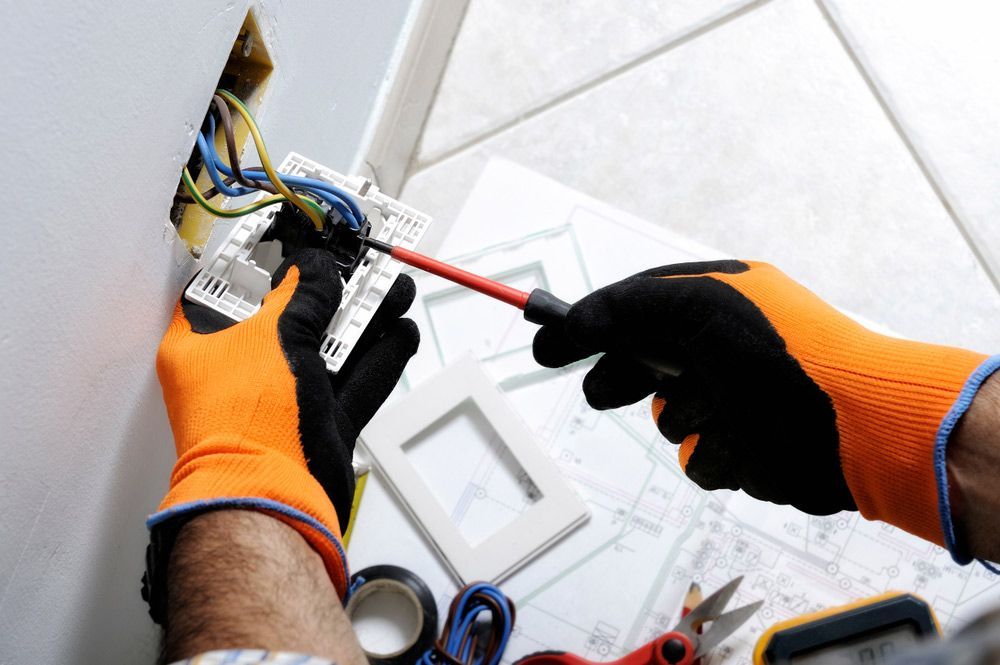 An Electrician is Working on a Wall With a Screwdriver — Brite-Lec Pty Ltd in Currajong, QLD