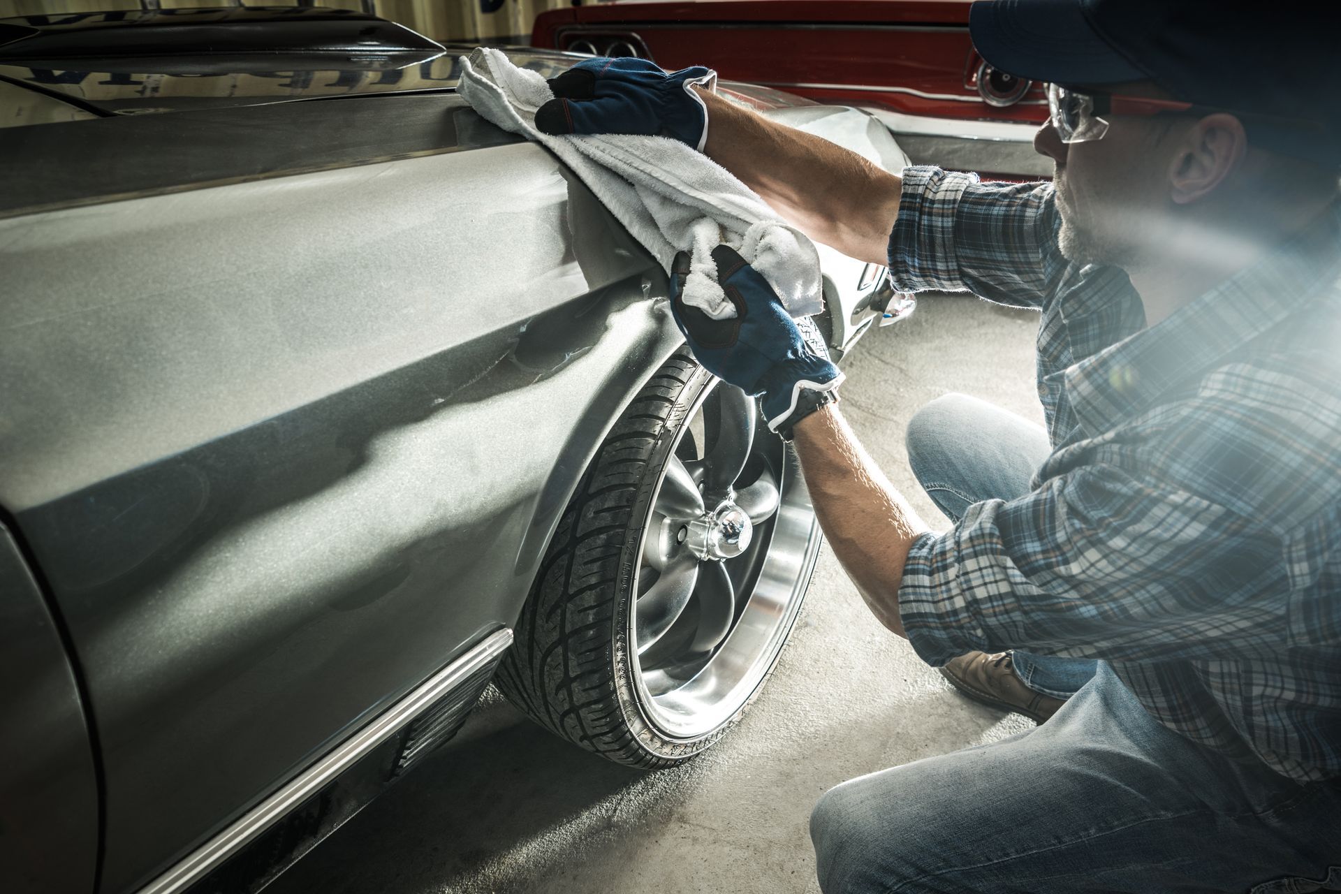 A partial view of an auto body technician wiping down a car panel A partial view of an auto body technician wiping down a car panel